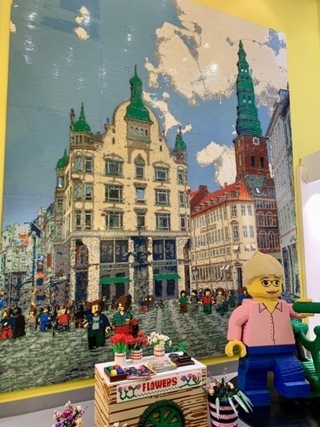A 'painting' of one of Copenhagen's main squares, done entirely in LEGO, with a life-sized LEGO model of a woman with a bicycle and flower cart in the foreground
